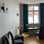 Blick auf das helle, modern renovierte Trauzimmer mit großen Rundbogenfenstern, dunkelblauen Vorhängen und einem stilvollen Schreibtisch vor einem Heizkörper.