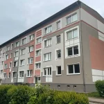 Eckansicht eines Wohngebäudes nach Fassadeninstandsetzung – Kontrastelemente und geometrische Flächenstruktur in gedeckten Farben geben dem Haus ein klares, modernes Erscheinungsbild.