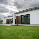 Gesamtansicht der Rückseite des Einfamilienhauses mit gepflegtem Garten, schlichter weißer Fassade und modernen Fensterflächen.