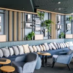 Kreativ gestalteter Lounge-Bereich mit gepolsterter Sitzbank, modernen Sesseln, Wandregalen mit Pflanzen und Seilakzenten – umgesetzt mit Liebe zum Detail durch MALER GROSSER.