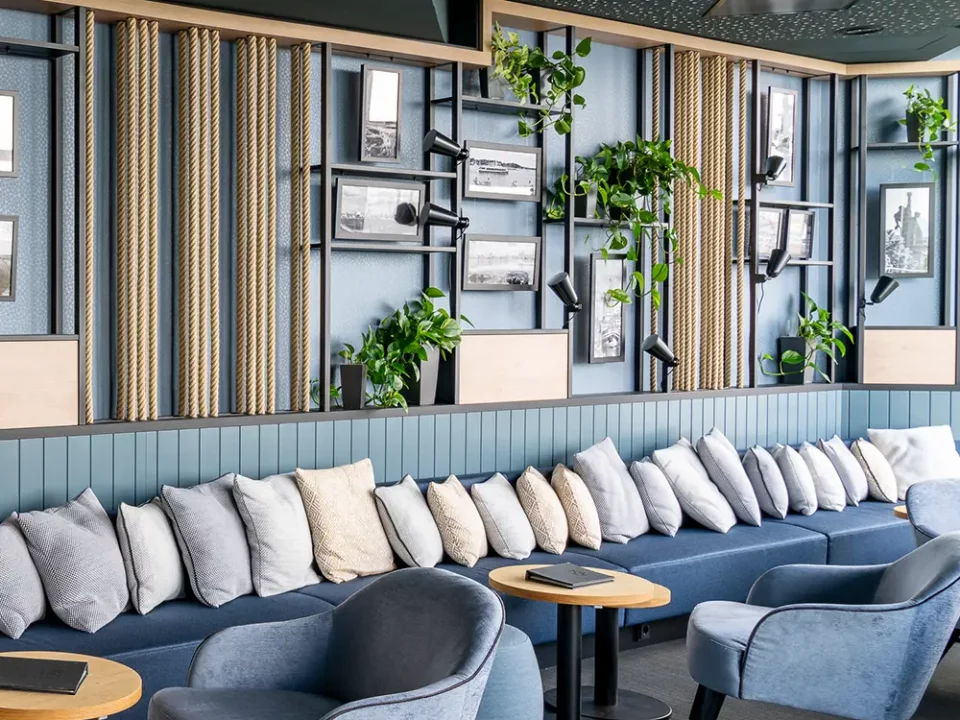 Kreativ gestalteter Lounge-Bereich mit gepolsterter Sitzbank, modernen Sesseln, Wandregalen mit Pflanzen und Seilakzenten – umgesetzt mit Liebe zum Detail durch MALER GROSSER.