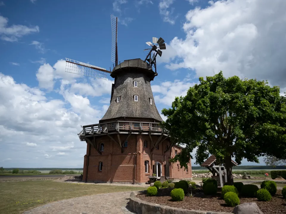 Historische Windmühle mit Backsteinbau und hölzernem Rundbalkon, eingebettet in die weite Landschaft – denkmalgerechte Instandsetzung durch MALER GROSSER.